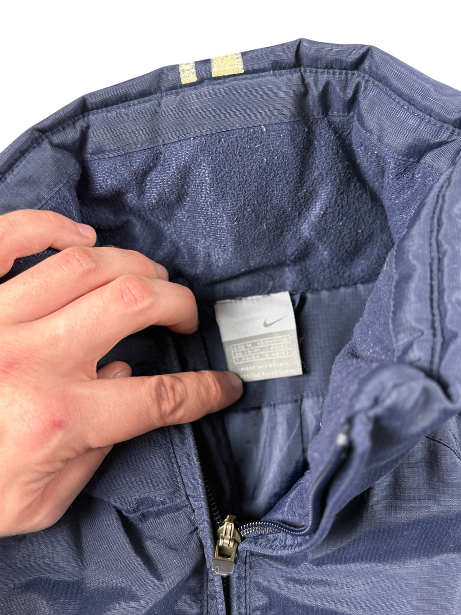 VBYC Nike Windbreaker in Dunkelblau mit Ripstop-Struktur, Stehkragen und Innenfutter, Detailansicht des Markenlabels
