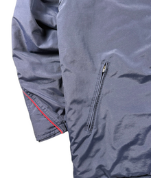 VBYC Nike Windbreaker in Dunkelblau mit Ripstop-Struktur, Reißverschlusstasche und roten Akzenten am Ärmel
